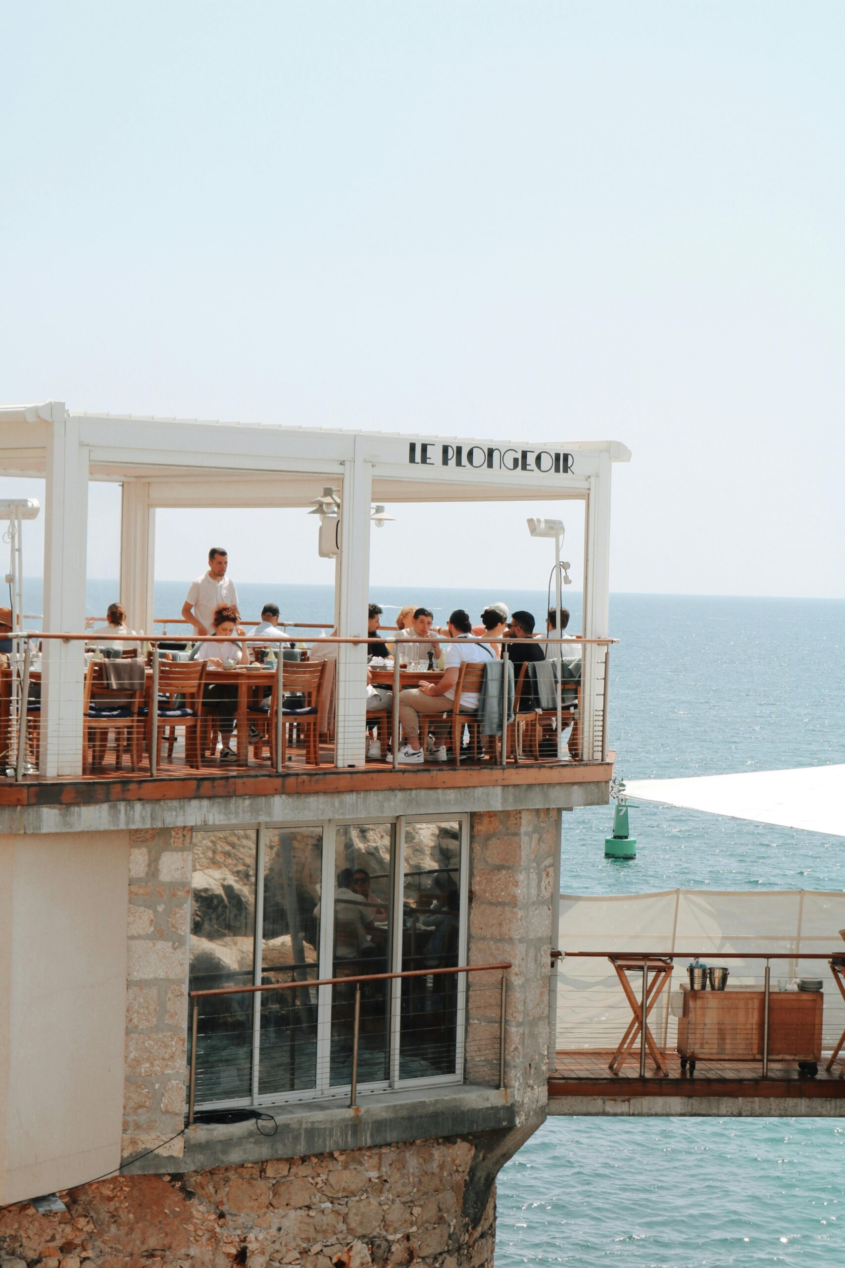 People dining at Le Plongeoir restaurant overlooking the sea in Nice, France.