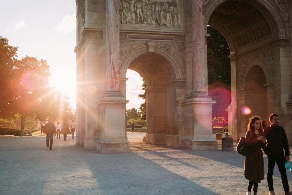 pexels-photo-2519214-2519214 A romantic scene with sunrays shining through a Parisian archway, featuring people strolling.