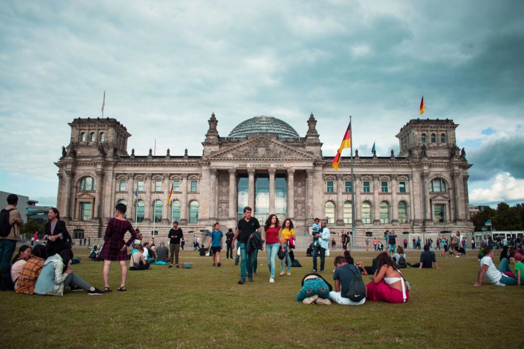 pexels-photo-2871654-2871654-1 Tourists relaxing on the lawn in front of the historic Reichstag Building in Berlin, Germany during a summer day.