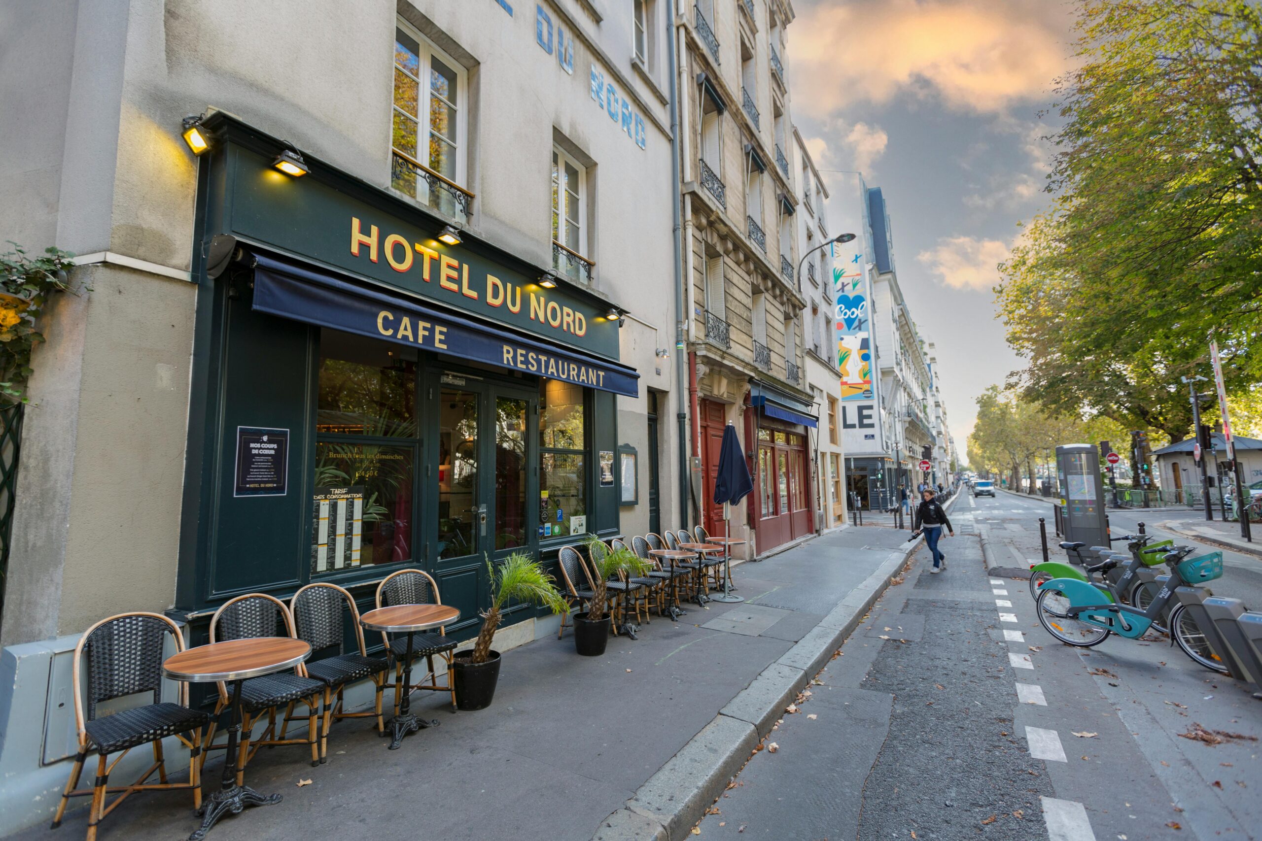 Beautiful Paris street with Hotel du Nord, outdoor cafe seating, and parked bikes.
