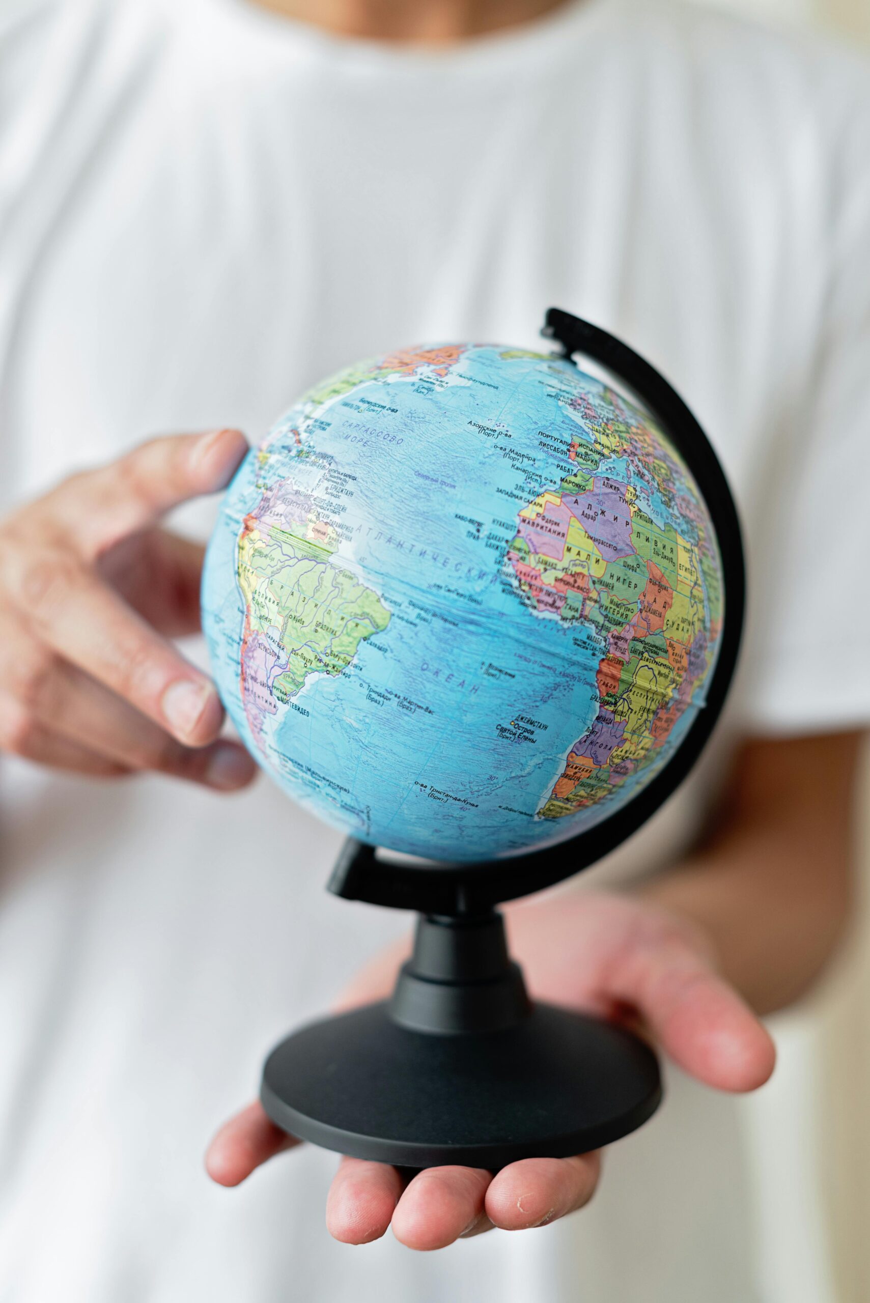 Person holding a small globe with focus on the Americas. Educational and travel concept.