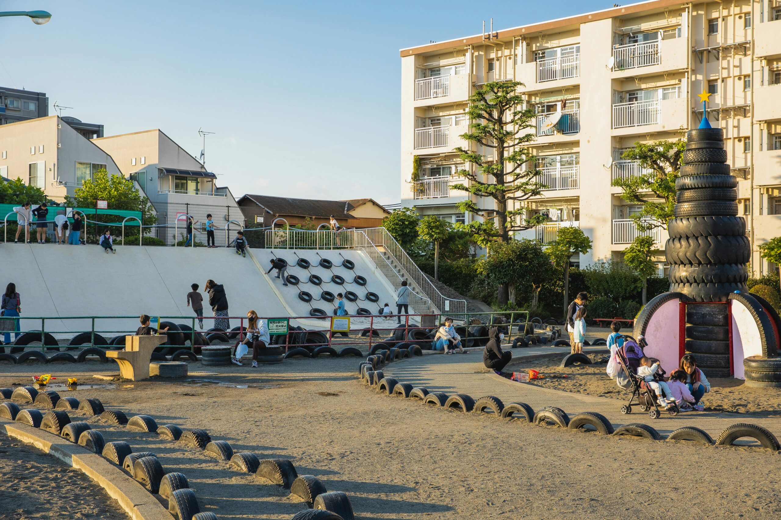 pexels-photo-5745021-5745021 A lively playground in Tokyo, featuring unique tire structures and families enjoying outdoor activities.