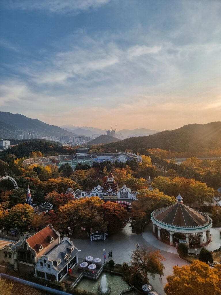 Stunning aerial shot of E-World theme park in Daegu, South Korea, surrounded by lush autumn foliage and mountains.